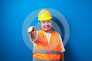 Young fat asian construction worker man wearing safety helmet pointing forward