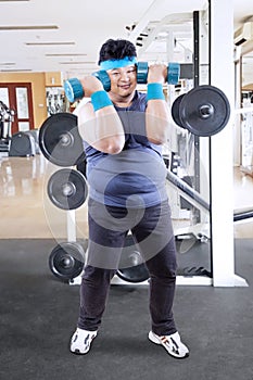 Young fat man doing a workout with barbells