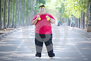 Young fat man exercising with dumbbells