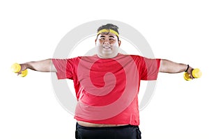 Young fat man holding two dumbbells on studio