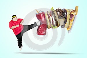 Young fat man kicking soft drink and fast food