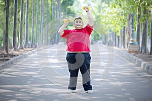 Young fat man lifting dumbbells on the road