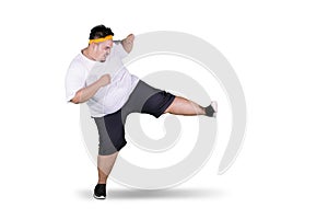 Young fat man performing a kick in the studio