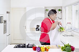 Young fat man preparing a bowl of organic salad