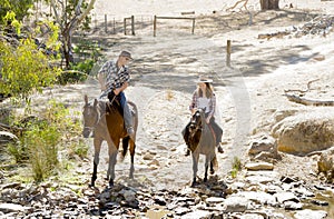 Young father as horse instructor of young teen daughter riding little pony wearing cowgirl hat