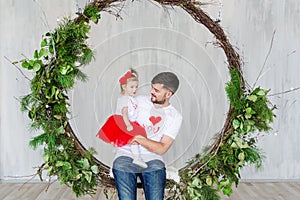 Young father with baby daughter having fun while sitting in swinging indoors