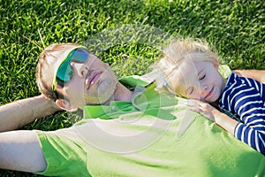 Young father with baby daughter lying on grass in a park