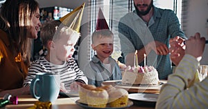 Young father brings in birthday cake for little Caucasian son, celebrating fun party at home with family slow motion.