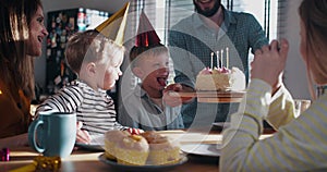 Young father brings in birthday cake for little Caucasian son, celebrating fun party at home with family slow motion.