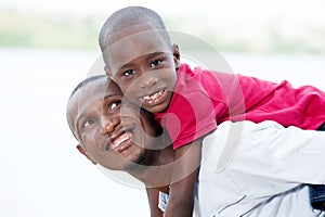 Young father carrying his son smiling on the back