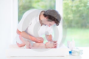 Young father changing a diaper at his little baby son