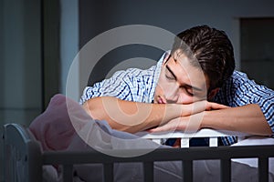 The young father dad sleeping while looking after newborn baby