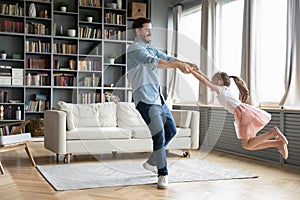 Young father dancing with happy preschooler daughter