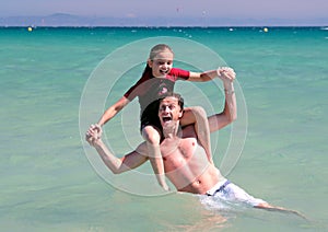 Young father and daughter playing on beach in sea