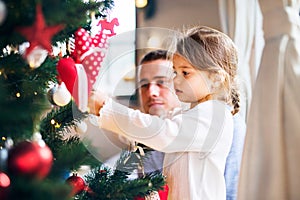 Young father with daugter decorating Christmas tree together.