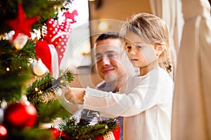 Young father with daugter decorating Christmas tree together.