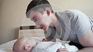 Young father entertains little baby girl on bed at home