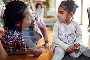 A young father is full of emotions while chatting and playing with his daughter at home. Family, together, love, playtime