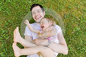 Young father have fun with his little daughter. Man and child are playing in grass