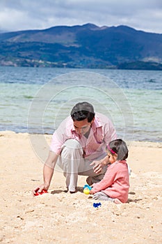 Young father having fun with his baby girl at the beautiful white beach of Lake Tota located in the department of Boyaca at 3,015