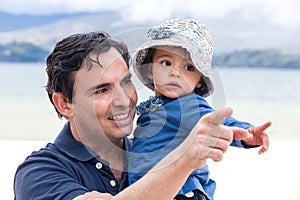 Young father having fun with his baby girl at the beautiful white beach of Lake Tota located in the department of Boyaca at 3,015