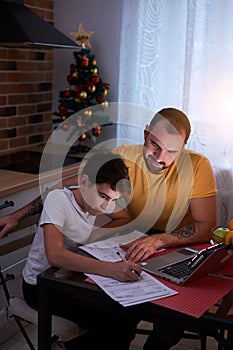 Young father helper and studying kid boy at home