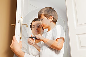 Young father helping his son to fix door-handle