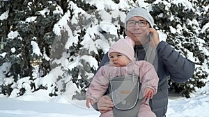 Young father with his baby in carrier with phone talking working father