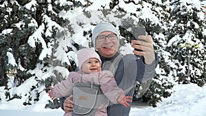 Young father with his baby in carrier with phone talking working father