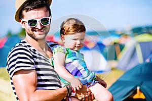 Young father with his baby daughter between tents, summer