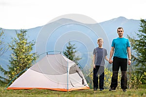 Young father and his child son hiking together in summer mountains. Active family on camping trip