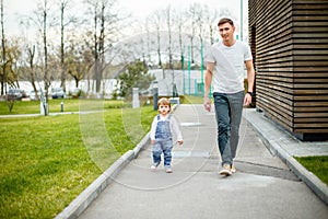 A young father with his daughter on a walk in the city park.