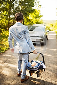 Young father with his little baby going into the car.