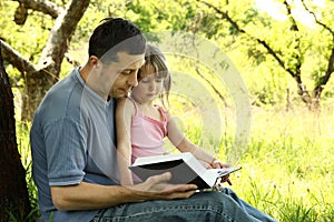 Young father with his little daughter reading the Bible