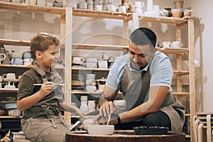 A young father and his seven-year-old son are engaged in creativity in a pottery workshop.