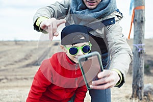 Young father with his son having fun outside in spring field, happy family smiling, lifestyle people making selfie