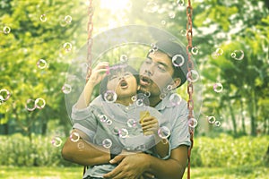 Young father and his son playing soap bubble