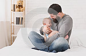 Young father holding crying sleepy cute newborn baby