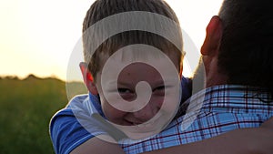 Young father holding in hands his small son at countryside. Little smiling boy looking into camera and hugging his dad