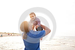 Young father holding his child on the beach having fun together