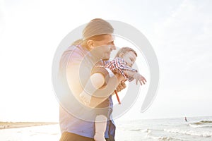 Young father holding his child on the beach having fun together