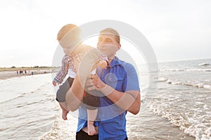 Young father holding his child on the beach having fun together