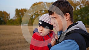 Young father holding his child on hands and watch the sunset. Tenderness and embrace of the beloved father. Outdoor
