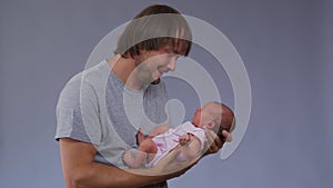 Young father holding and kissing his new born infant baby.