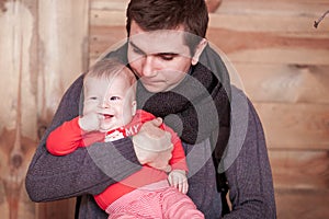 Young father holding son against wooden background