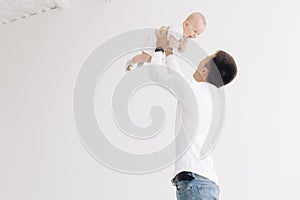 Young father holds his laughing baby and plays with him