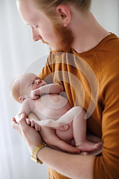 Young father holds a newborn son in his arms