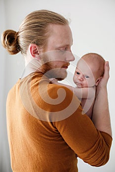 Young father holds a newborn son in his arms