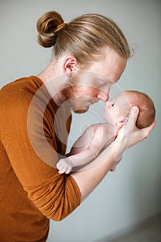 Young father holds a newborn son in his arms