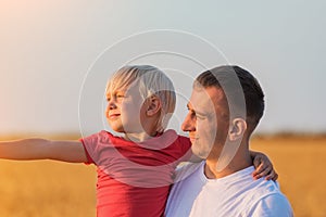 Young father holds son on hands and looks into distance. Paternal care and responsibility photo